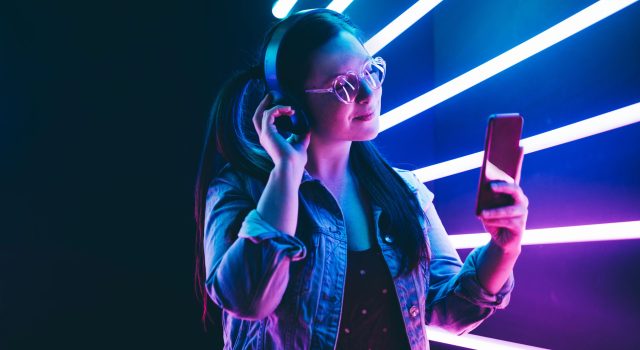 Sillhoutte of hip-hop girl with headphones at the neon light. Fashion portrait of modern young woman making selfie.